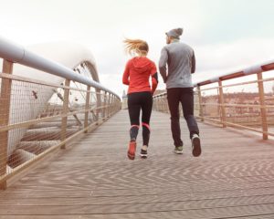 Vyras ir moteris dėvintys sortinę aprangą bėga tiltu