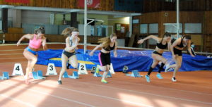 Penkios merginos bėga lengvosios atletikos takeliu 