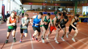 Septyni vaikinai bėga lengvosios atletikos takeliu 