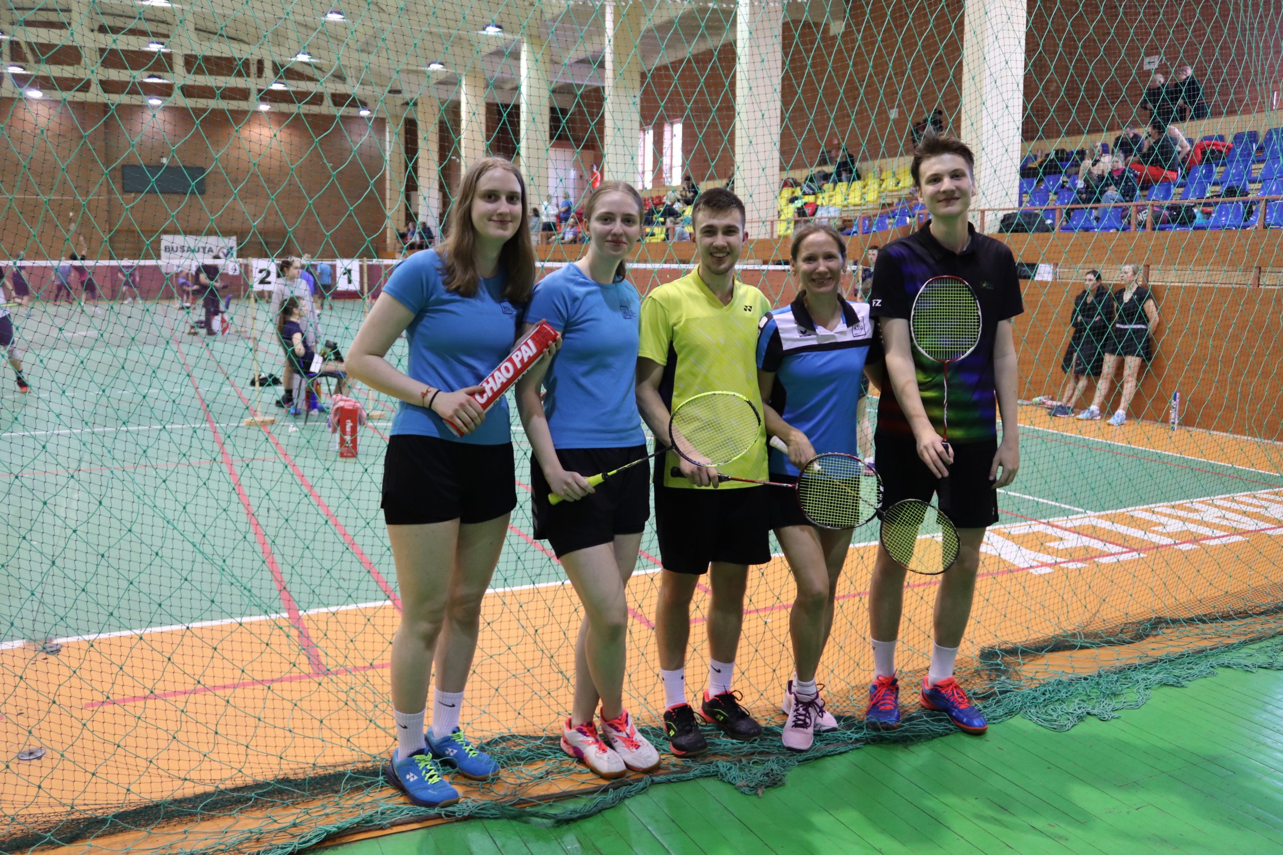 Keturi KTU Bandminto rinktinės studentai su trenere stovi badmintono aikštelėje