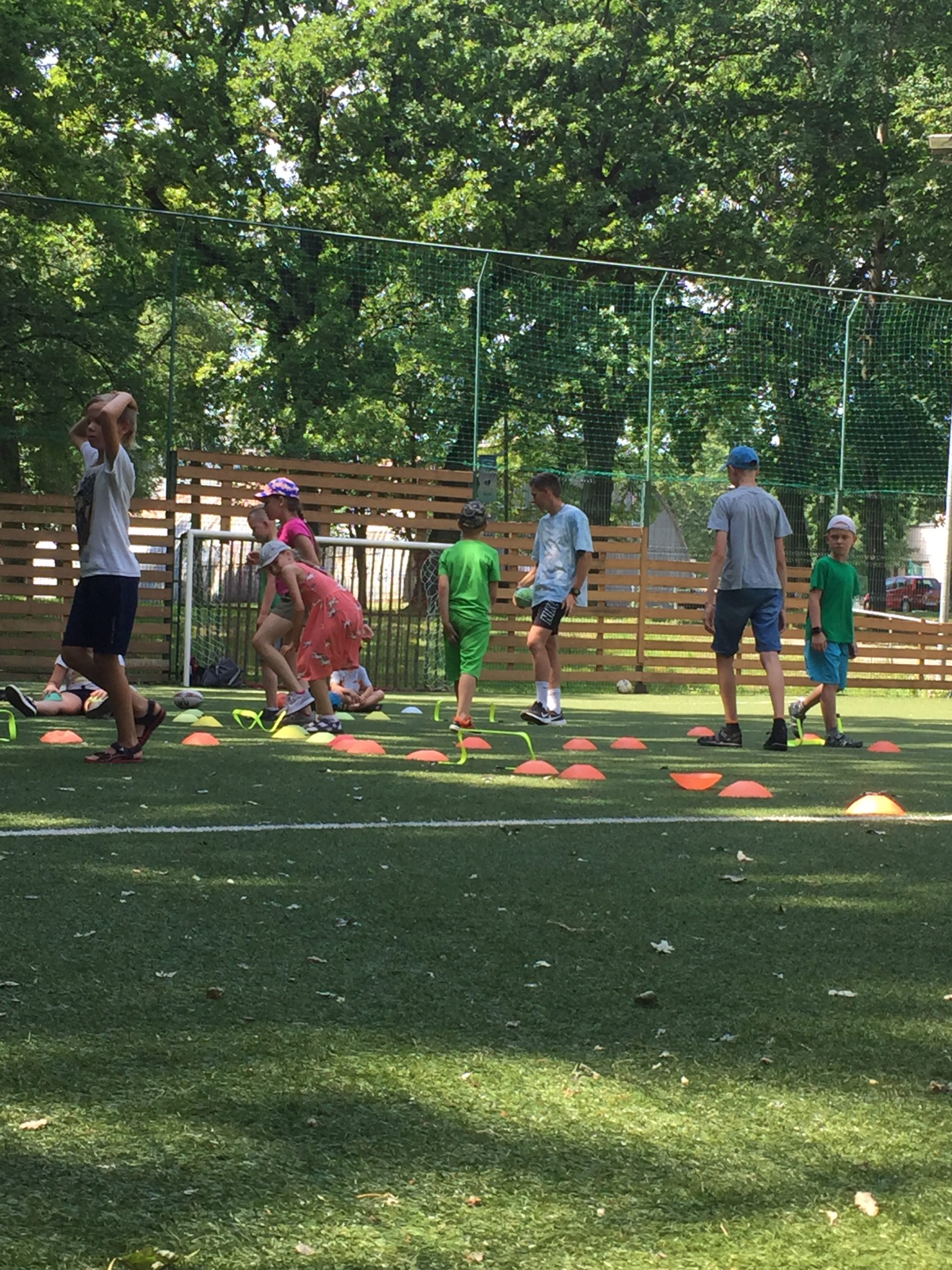 Būrys vaikų futbolo aikštėje žaidžia estafetes