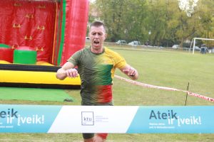 Vyras dėvintis marškinėlius su Lietuvos vėliava, bėga per finišo juostą 