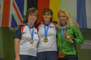 Trys moterys dėvinčios bronzos, sidabro bei aukso medalį stovi greta viena kitos
