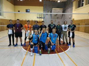 Dvylika studentų stovi sporto salėje su tinklinio tinklu