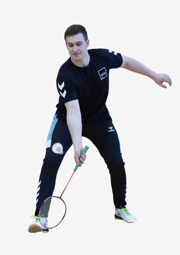 Vaikinas tamsiais plaukais ir juoda KTU sportine apranga rakete muša badmintono kamuoliuką