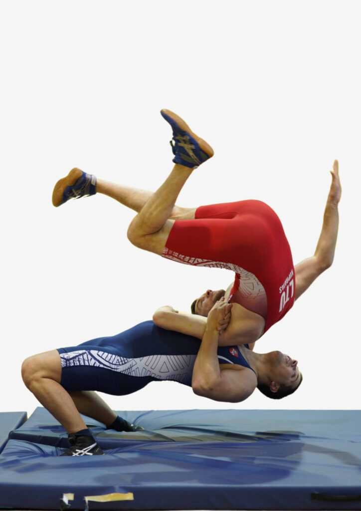 Du vyrai raudonais ir mėlynais sportiniais drabužiais atlieka imtynių veiksmą 